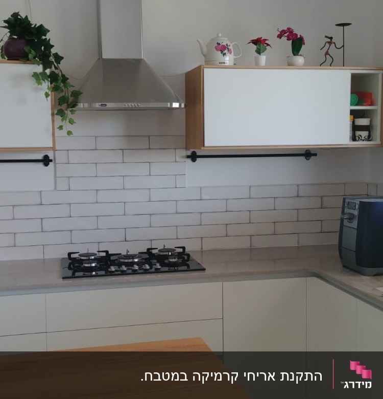 מטבח עם ארונות לבנים, כיריים וקולט אדים